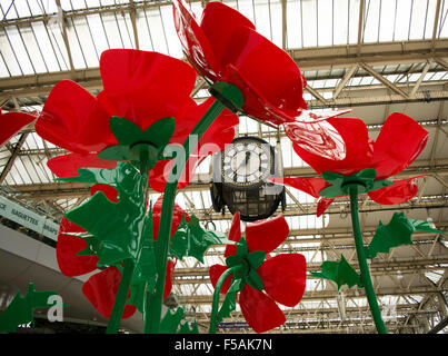 People swirling past a giant poppy installation on the concourse of Waterloo Station as part of London Poppy Day Stock Photo