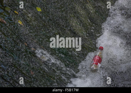 Empty soft drinks bottle caught in cascading weir flow. Plastic waste, war on plastic concept. For environmental river pollution, plastic rubbish. Stock Photo