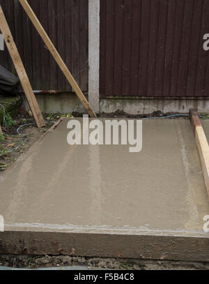 Part smoothed wet cement that is forming a shed a base Stock Photo