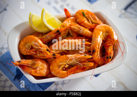Large orange shrimp with lemon in bowl, top view Stock Photo