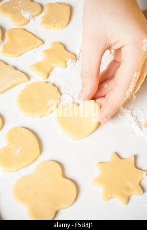 Girl shows heart shape out of dough, top view Stock Photo