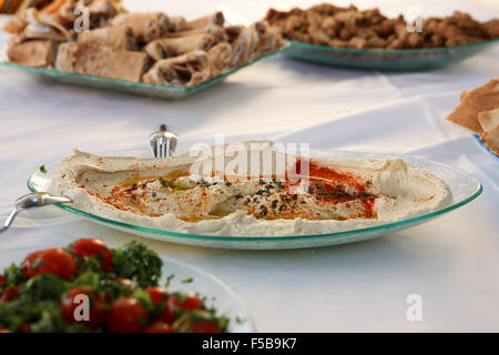 A buffet table set with salads and appetizers - main focus on a dish of hummus Stock Photo