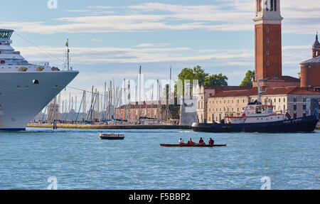 Cruise ship being guided in front of San Giorgio Maggiore island by a tugboat with a canoe in foreground Venice Veneto Italy Stock Photo