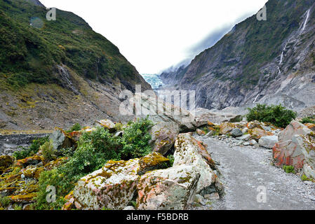 Walking trail along a rocky riverbed path next to Waiho River of the  glacier's melt water up to the toe of the Franz Josef glacier,  New Zealand Stock Photo