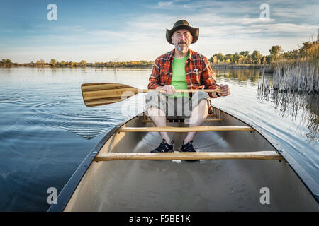 senior paddler enjoying paddling a canoe on a calm lake, Riverbend Ponds Natural Area, Fort Collins, Colorado Stock Photo