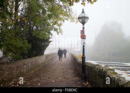 Stratford-upon-Avon, Warwickshire, UK. 1st November, 2015. Fog envelops the town of Stratford-upon-Avon on the first day of the month. People take a morning stroll across the Tramway Bridge over the River Avon. Credit:  Colin Underhill/Alamy Live News Stock Photo