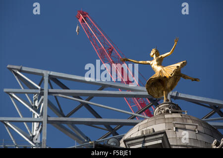 London, UK. 01st Nov, 2015. The gold statue of prima ballerina Anna Pavlova strikes an elegant pose on top of the Victoria Palace Theatre, Victoria, London, with construction of the new Victoria Centre behind against a blue sky Credit:  On Sight Photographic/Alamy Live News Stock Photo