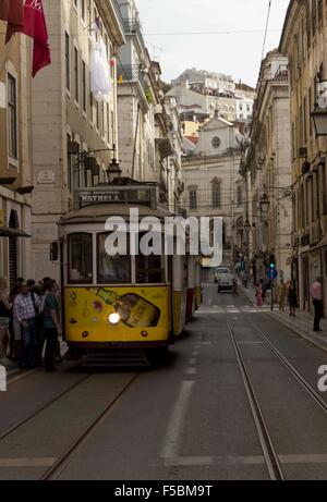 LISBON, PORTUGAL   OCTOBER 24 2014: Rua Conceicao street in Lisbon with a series of tram and people walking, with Magdalene chur Stock Photo