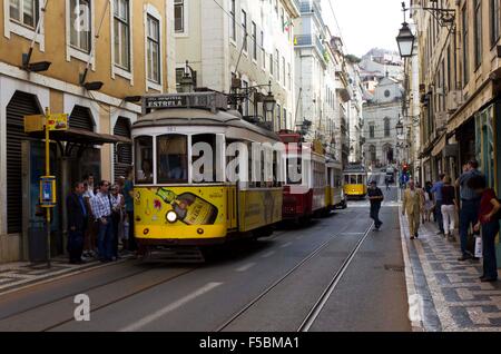 LISBON, PORTUGAL   OCTOBER 24 2014: Rua Conceicao street in Lisbon with a series of tram and people walking, with Magdalene chur Stock Photo