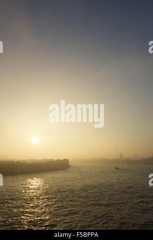 London, UK.  1st November 2015. A thick fog rolls in again from the east to cover The Docklands and hide its landmark skyscrapers. Mist continues east over Rotherhithe, making for an eeir sunset over the River Thames. 1st November 2015. Credit:  Glenn Sontag / Alamy Live News Stock Photo