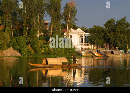 A wooden sampan makes its way up the brown waters of the Perfume River in Hue, Vietnam. Stock Photo