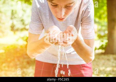 teenage boy drinking water from a well  in cupped hands Stock Photo