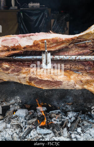 Whole pig being spit roasted on hot embers Stock Photo