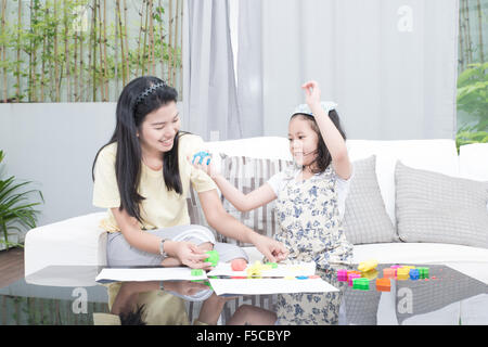 family, children and happy people concept - Asian mother and kid daughter playing with plasticine in home Stock Photo