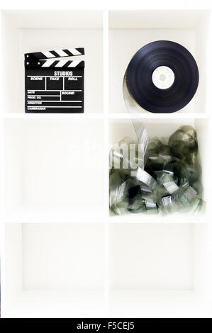 Movie clapper board and film reel on vertical white bookshelf with six cubic boxes and copy space Stock Photo