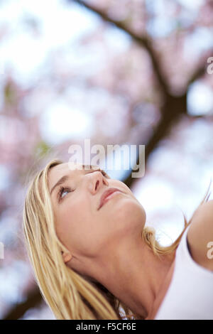 Young blonde woman looking up in the sky Stock Photo