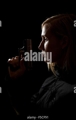 Young female shooter holding a pistol at night Stock Photo