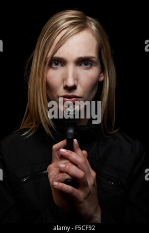 Young female shooter holding a pistol at night Stock Photo