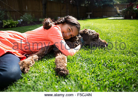 Portrait smiling girl laying dog sunny lawn