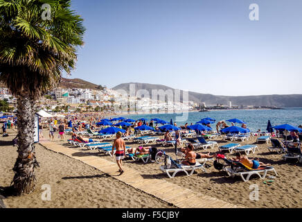 People sunbathing on the popular resort Playa de Las Americas in Tenerife Stock Photo