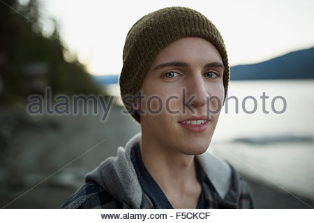 Close up portrait young man wearing beanie lakeside