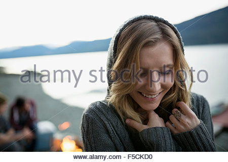 Close up smiling young woman in hoody lakeside