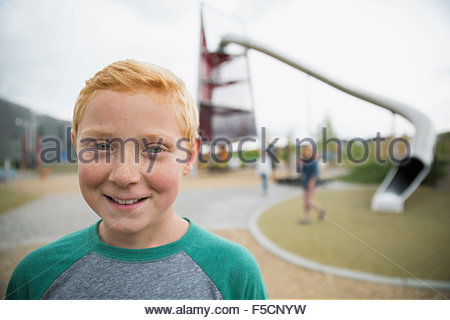Close up portrait smiling boy red hair playground