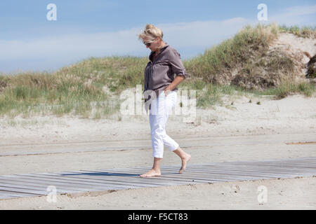 One Senior walks in the dunes on a beach and enjoying the peace and quiet Stock Photo