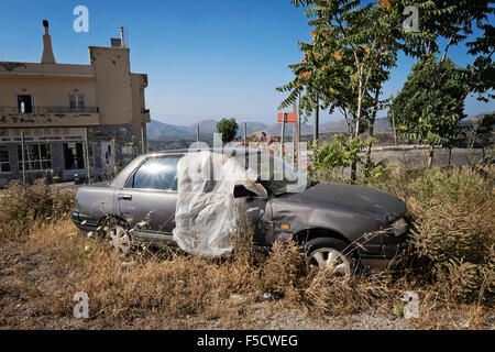 An abandoned car on a vacant lot in the village of Anogia on the island of Crete in Greece Stock Photo
