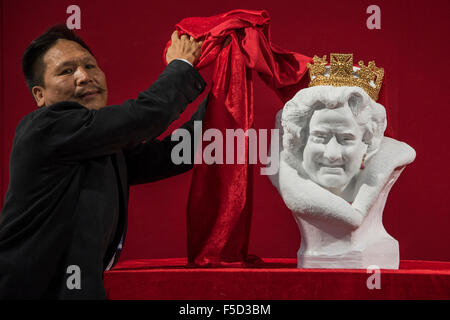 London, UK. 02nd Nov, 2015. Chen Dapeng unveils a new bust of Her Majesty Queen Elizabeth II, which he has executed to celebrate the 2015 UK-China Year of Cultural Exchange (it is on a stand with his other million pound works). Winter Olympia Art & Antiques Fair- in its 25th year the fair plays host to 22,000 visitors who come to see over 30,000 pieces for sale from the 120 hand-picked dealers valued frpom £100-£1m.  The fair runs from 2-8 November 2015, opening with the Collector’s Preview Reception on 2 November at 5pm.. Credit:  Guy Bell/Alamy Live News Stock Photo