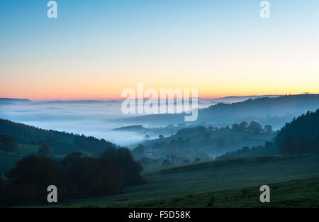 Near Knighton, Powys, Wales, UK. 01st November, 2015. Sunset over a solitary cottage with thick fog filling the valleys beyond it. In the distance, Hay Bluff to the left and Pen y Fan in the Brecon Beacons in the centre Credit:  Alex Ramsay/Alamy Live News Stock Photo