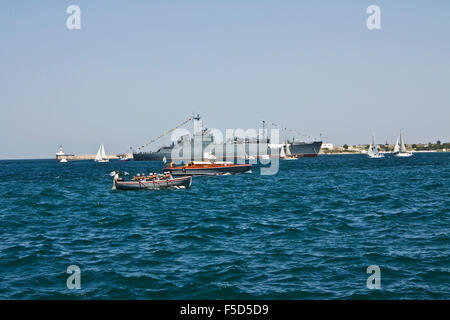 Navigation parade in town Sevastopol in Crimea on Black sea, big military ship and little boats. Stock Photo