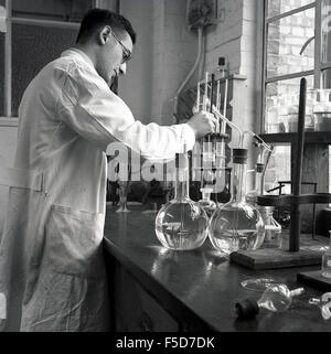 1950s, historical, male scientist in white coat at work in a chemical laboratory, England, UK, mixing different liquids. Stock Photo