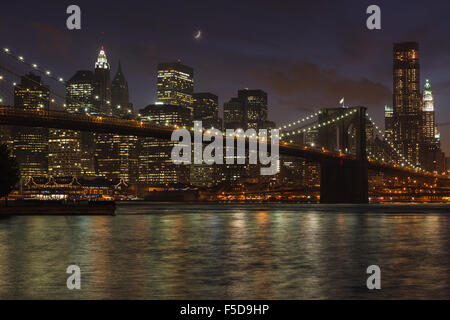 New York skyline and the Brooklyn Bridge at night, from Fulton Ferry Park. New York, NY, United States of America. Stock Photo