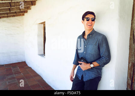 A young casual businessman leaning against a wall smiling Stock Photo