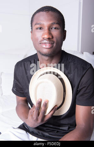 african man with hat sitting on couch Stock Photo
