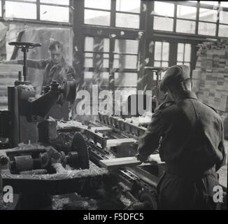 1950s, historical, male workers at machines repairing or retreading ...