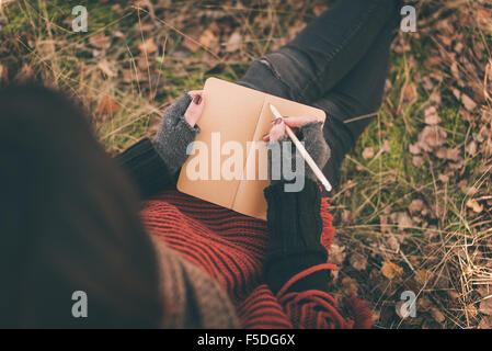 Woman in nature writing in a notebook Stock Photo