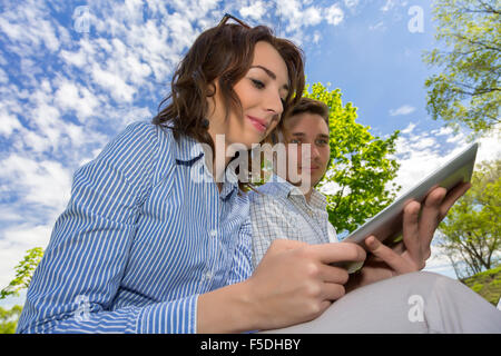 Man and woman with tablet PC on blue sky background Stock Photo