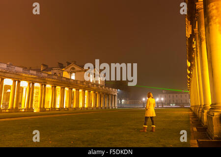 Greenwich, London, 2nd November 2015. A walker at the Old Royal Naval College looks at the laser projected from the Royal Observatory, marking the Prime Meridian line, as it cuts through the dense evening fog. Credit:  Imageplotter/Alamy Live News Stock Photo
