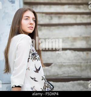 Beautiful adult girl standing on stairs and looking straight Stock Photo