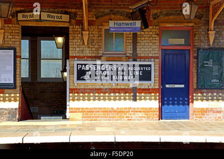 A really old wooden painted sign on the platform amid two entrances requesting passengers to cross the line by use of the subway Stock Photo