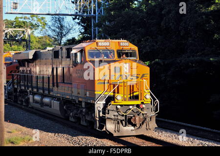 A Burlington Northern Santa Fe freight train as it emerges from shadows and a signal tower rumbling through Rochelle, Illinois, USA. Stock Photo