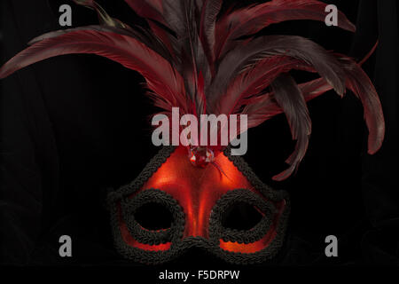 Red masquerade mask against black background. Stock Photo