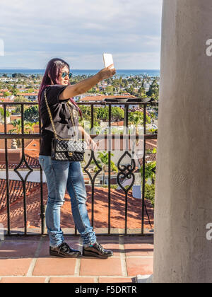 Young adult Asian woman tourist taking selfie from the top of the Santa Barbara County Courthouse overlooking the city of Santa Stock Photo