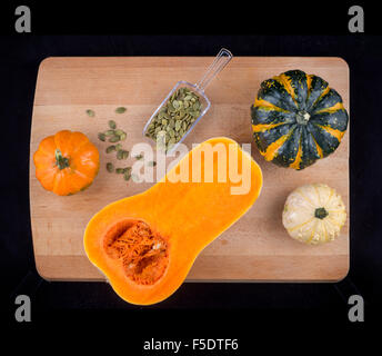 Colorful pumpkins and squash with dried hulled seeds on a wooden table isolated over black Stock Photo