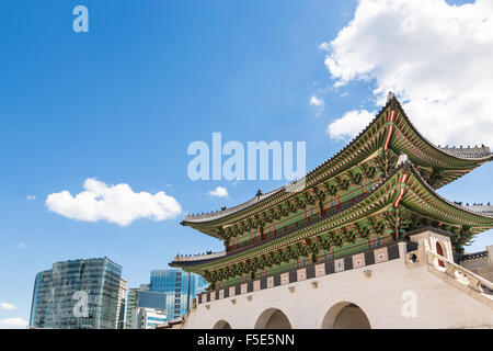 The traditional architecture of the gate of the Royal Palace in Seoul contrasts with the modern office buildings outside its wal Stock Photo