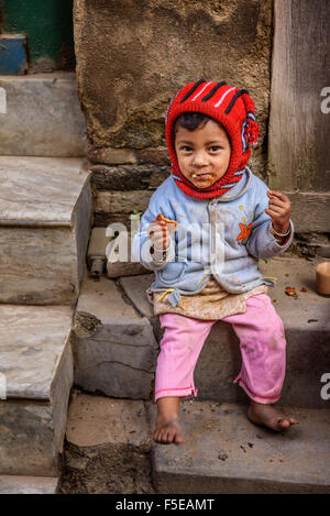 A poor girl in Nepal eating a cracker in the street of Kathmandu Stock Photo