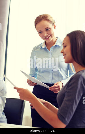 smiling businesswomen with papers in office Stock Photo