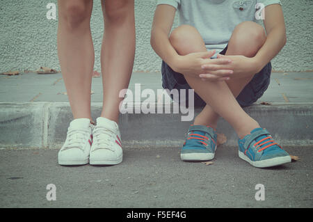 Close-up of two teenagers sitting and standing in the street